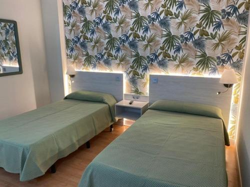 una habitación con 2 camas y una pared con flores en Miralcampo, en Azuqueca de Henares