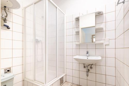 a white bathroom with a sink and a shower at Getreide T13 in Vienna
