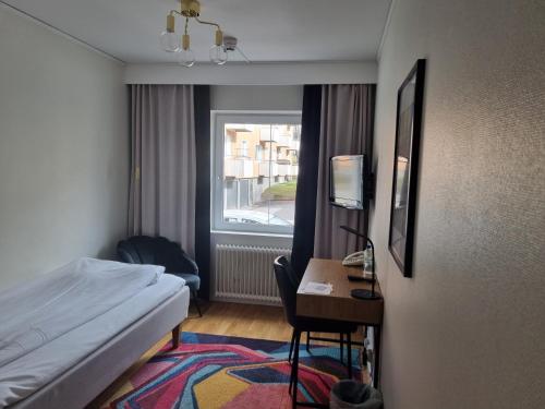 a hotel room with a bed and a desk and a window at Mjölby Stadshotell in Mjölby