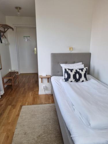 a bedroom with a bed with white sheets and pillows at Mjölby Stadshotell in Mjölby
