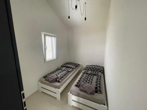 two beds in a small room with a window at Villa Melissa in Pag