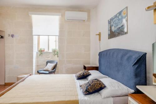 a bedroom with a bed and a blue chair at Gallo House in Cospicua