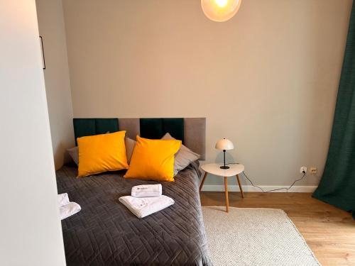 a bedroom with a bed with yellow pillows and a table at HUDSON APARTAMENT CENTRUM in Koszalin