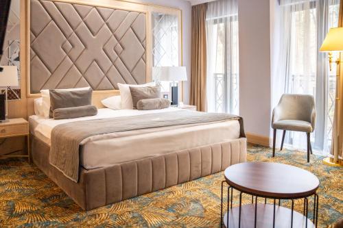 1 dormitorio con 1 cama grande, mesa y sillas en A Hoteli - Hotel Park en Vrnjačka Banja