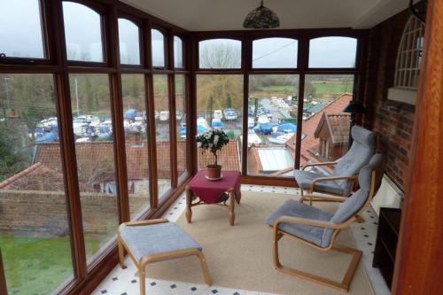 a screened in porch with two chairs and a table at Ballygate Stable in Beccles