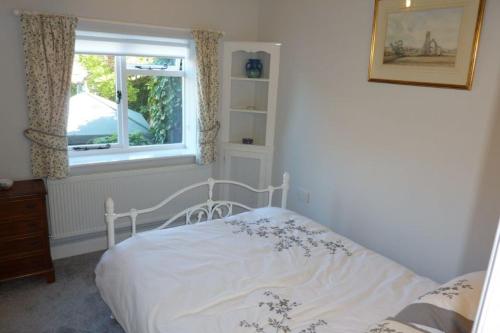 a white bed in a bedroom with a window at Ballygate Stable in Beccles