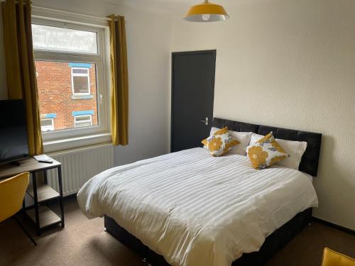 um quarto com uma cama com almofadas e uma janela em Quirky and Cosy Two Bed in Ferryhill Near Durham! em Ferryhill