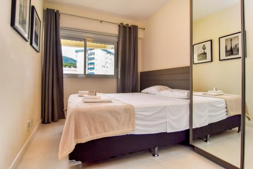 Schlafzimmer mit einem Bett und einem Spiegel in der Unterkunft Plaza Saint Tropez, Conforto no Itacorubi P2255 in Florianópolis