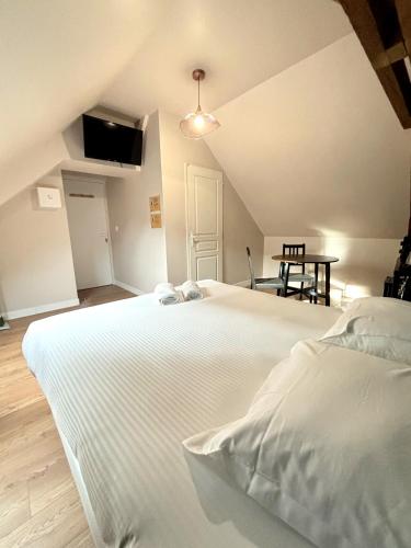 Cette chambre comprend un grand lit blanc et une table. dans l'établissement Onyx Green, à Saint-Aignan