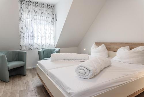- une chambre dotée d'un lit avec des draps blancs et 2 chaises dans l'établissement 50089...., à Carolinensiel