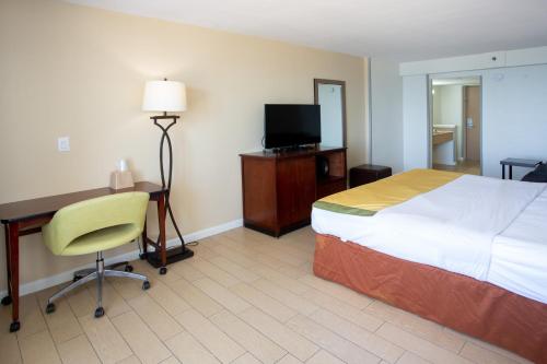 a hotel room with a bed and a desk and a television at Aqua Vista Resort Hotel in Virginia Beach