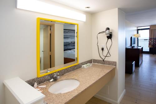 a bathroom with a sink and a yellow mirror at Aqua Vista Resort Hotel in Virginia Beach