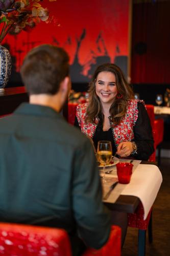 a man and a woman sitting at a table in a restaurant at Hampshire Hotel - Delft Centre in Delft