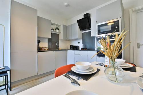 uma cozinha com armários brancos e uma mesa com cadeiras em StayRight 2 Bedroom City Stays- Vibrant Area near Centre em Cardiff