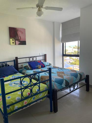 a bedroom with a bed in a room with a fan at Departamento en playa almendro in Tonsupa