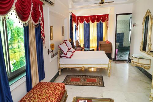een slaapkamer met een bed, een bank en ramen bij FabHotel Prime Indeedcare Resort Bakkhali in Bakkhali
