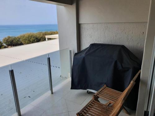 a chair on a balcony with a view of the ocean at Nautica in Mossel Bay