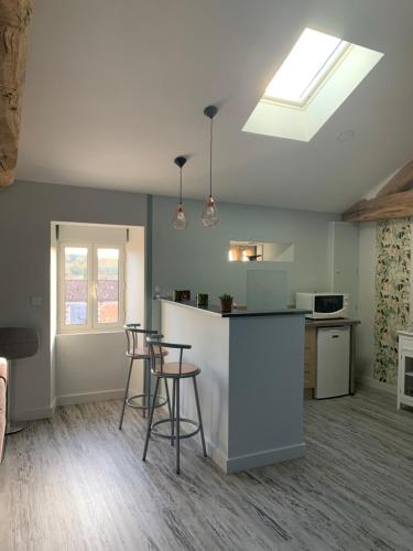 un salon avec une cuisine et un comptoir avec des tabourets dans l'établissement La fléchette - appartement entier climatisé 2 chambres - 100m2, à Saint-Adjutory