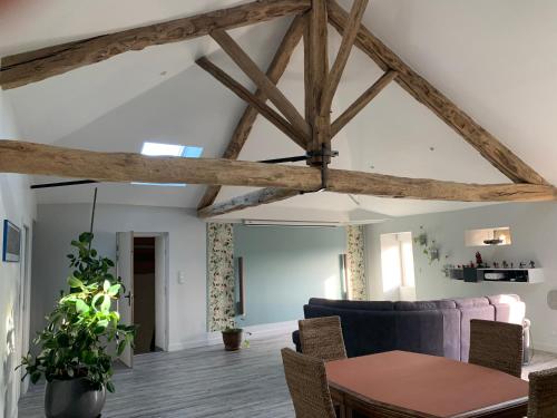 Elle comprend un salon doté de plafonds en bois et d'une table. dans l'établissement La fléchette - appartement entier climatisé 2 chambres - 100m2, à Saint-Adjutory