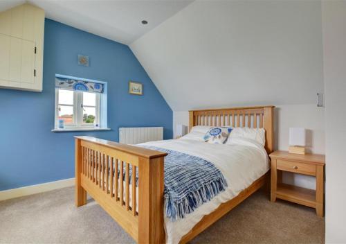 a bedroom with a wooden bed and a blue wall at Top End Cottage 6 in Ringstead