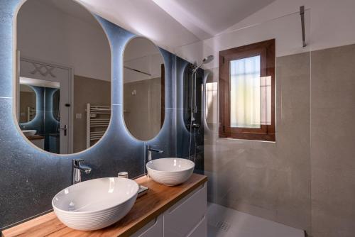 a bathroom with two sinks and two mirrors at Villa Bollaccia - Vue mer avec piscine in LʼÎle-Rousse