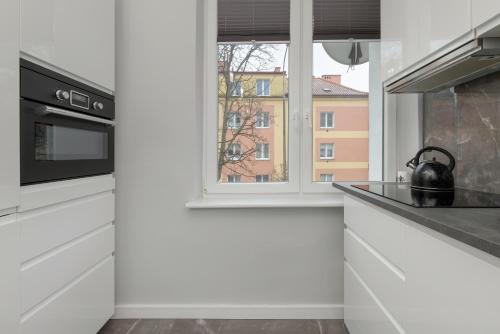 una cucina con armadietti bianchi e una finestra di Studio El Cubano with Parking in Gdansk by Rent like home a Danzica