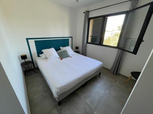 1 dormitorio con cama blanca y ventana en CLOS ARIA NOVA, en Lucciana