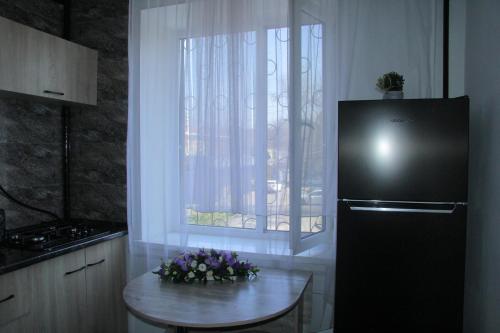 a kitchen with a black refrigerator and a table with flowers at Апартаменты Центр Медеуский Район in Almaty