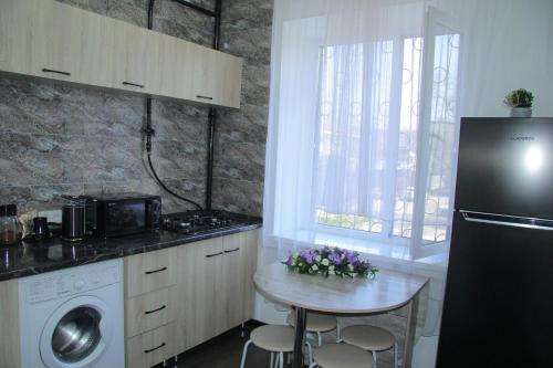 a kitchen with a small table and a refrigerator at Апартаменты Центр Медеуский Район in Almaty