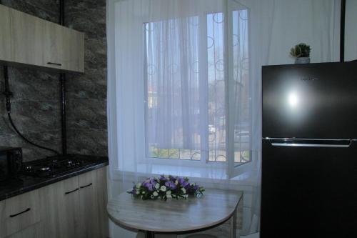 a kitchen with a table and a window with flowers on it at Апартаменты Центр Медеуский Район in Almaty