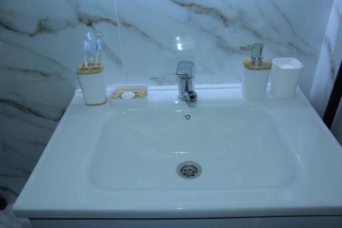 a bathroom sink with two toothbrushes and two cups on it at Апартаменты Центр Медеуский Район in Almaty