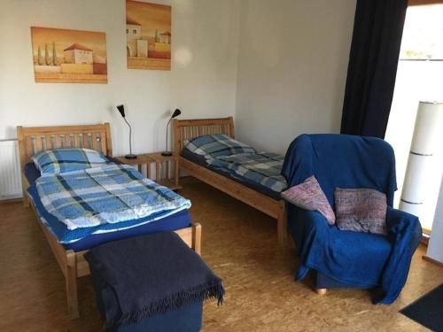 two beds and a chair in a room at Schöne Wohnung in Widukindland mit Grill, Garten und Terrasse in Osnabrück