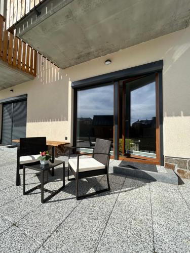 a patio with two chairs and a table at Apartmán A3 Kašperky Slunný moderní apartmán na horách in Kašperské Hory