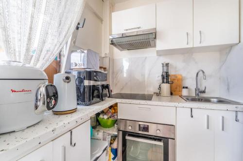 una pequeña cocina con armarios y electrodomésticos blancos en Appartement Lumineux avec Balcon à Courbevoie, en Courbevoie