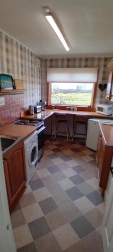 a kitchen with a checkered floor and a window at Mark cottage in Creetown