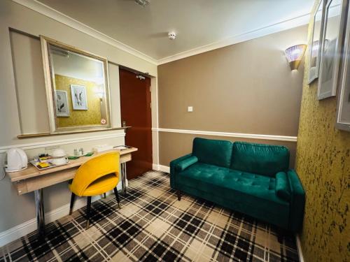 a living room with a green couch and a yellow chair at 4 Sisters Inn in Theydon Bois