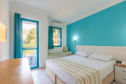 a blue bedroom with a bed and a window at Monta Verde Hotel & Villas in Oludeniz
