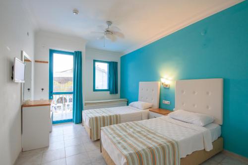 a bedroom with two beds and a blue wall at Monta Verde Hotel & Villas in Oludeniz