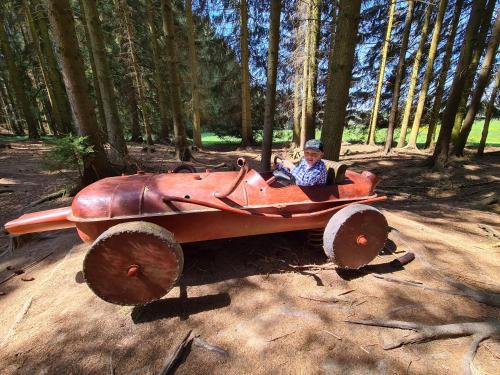 a man is sitting in a red car on wheels at Penzion Poslední míle in Milovy