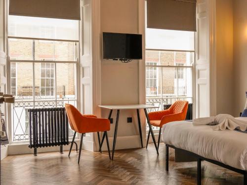 a bedroom with a bed and two chairs and a table at Imperial York Street Apartments in London