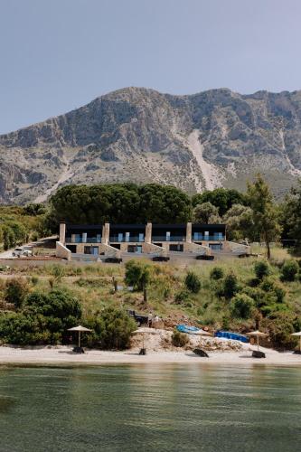 a building on a beach with a mountain in the background at Villa Kastos in Paleros