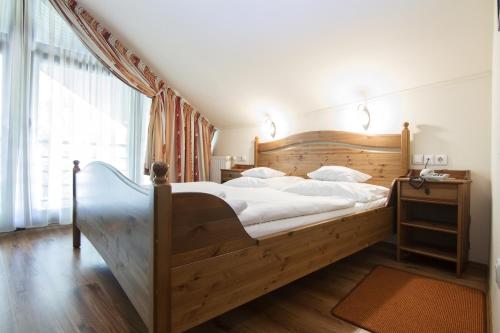 Un dormitorio con una gran cama de madera con sábanas blancas. en Arany Szarvas Fogadó és Captain Drakes Pub, en Győr