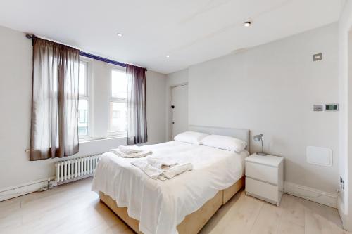 a white bedroom with a bed and a window at Modern 3 Bed Apartment in Hampstead in London