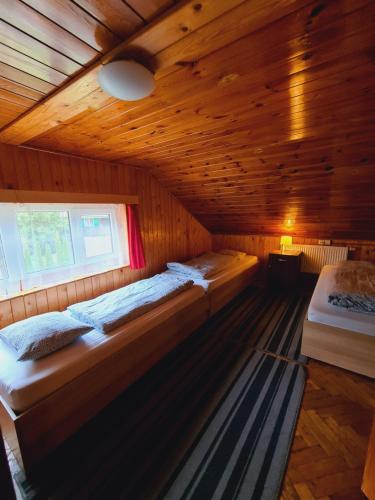a room with two beds in a wooden cabin at Penzion Poslední míle in Milovy