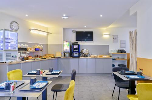 a restaurant with tables and chairs and a kitchen at Adonis Hotel Strasbourg in Strasbourg