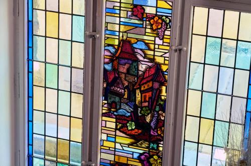 a stained glass window with a picture of a house at Adonis Hotel Strasbourg in Strasbourg