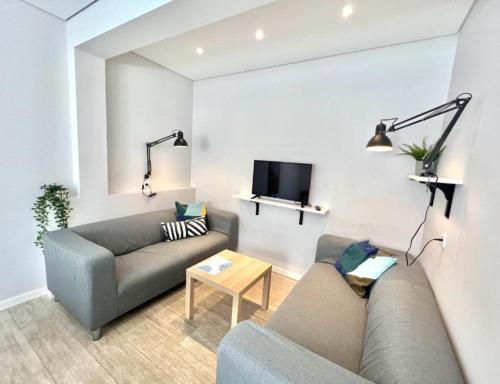 a living room with a couch and a tv at Campus 121 - Rooms in Faro