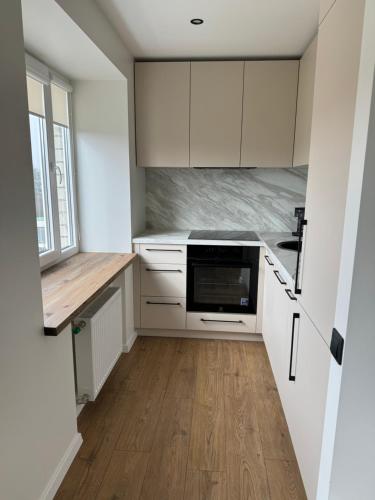 a kitchen with white cabinets and a wooden floor at Sea Oasis apartment in Liepāja