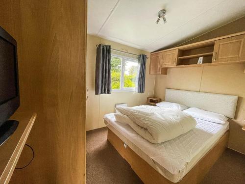 ein kleines Schlafzimmer mit einem Bett und einem Fenster in der Unterkunft Great Caravan At Breydon Water Holiday Park, Ref 10086b in Belton