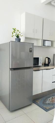 a stainless steel refrigerator in a kitchen with white cabinets at Camelia youth city nilai studio residence 5 pax. in Nilai